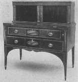 The tambour work doors in the upper part of this Sheraton
secretary roll back; also notice the handles and inlay and tapering
legs.